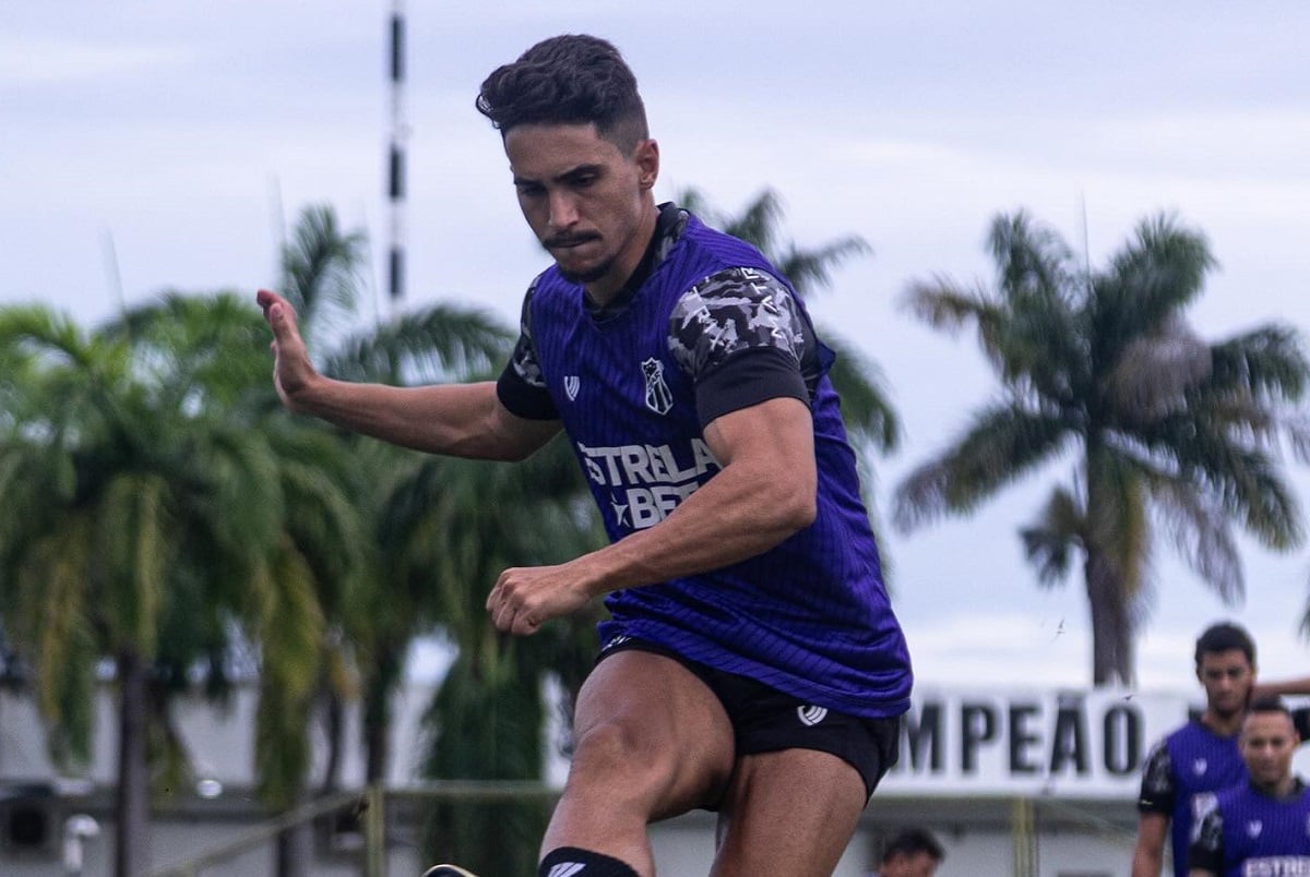 a man in a purple shirt and shorts running with his hand up